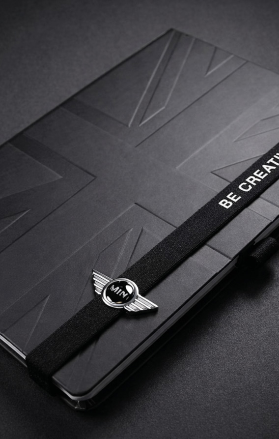 Detailaufnahme eines schwarzen Notizbuchs mit strukturierter Prägung, rotem Textilband und integrierter Stiftschlaufe