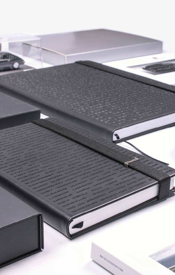 Schwarzes Notizbuch mit geometrischer Prägung und elastischem Band mit Metallelement, edle Produktinszenierung auf dunklem Untergrund