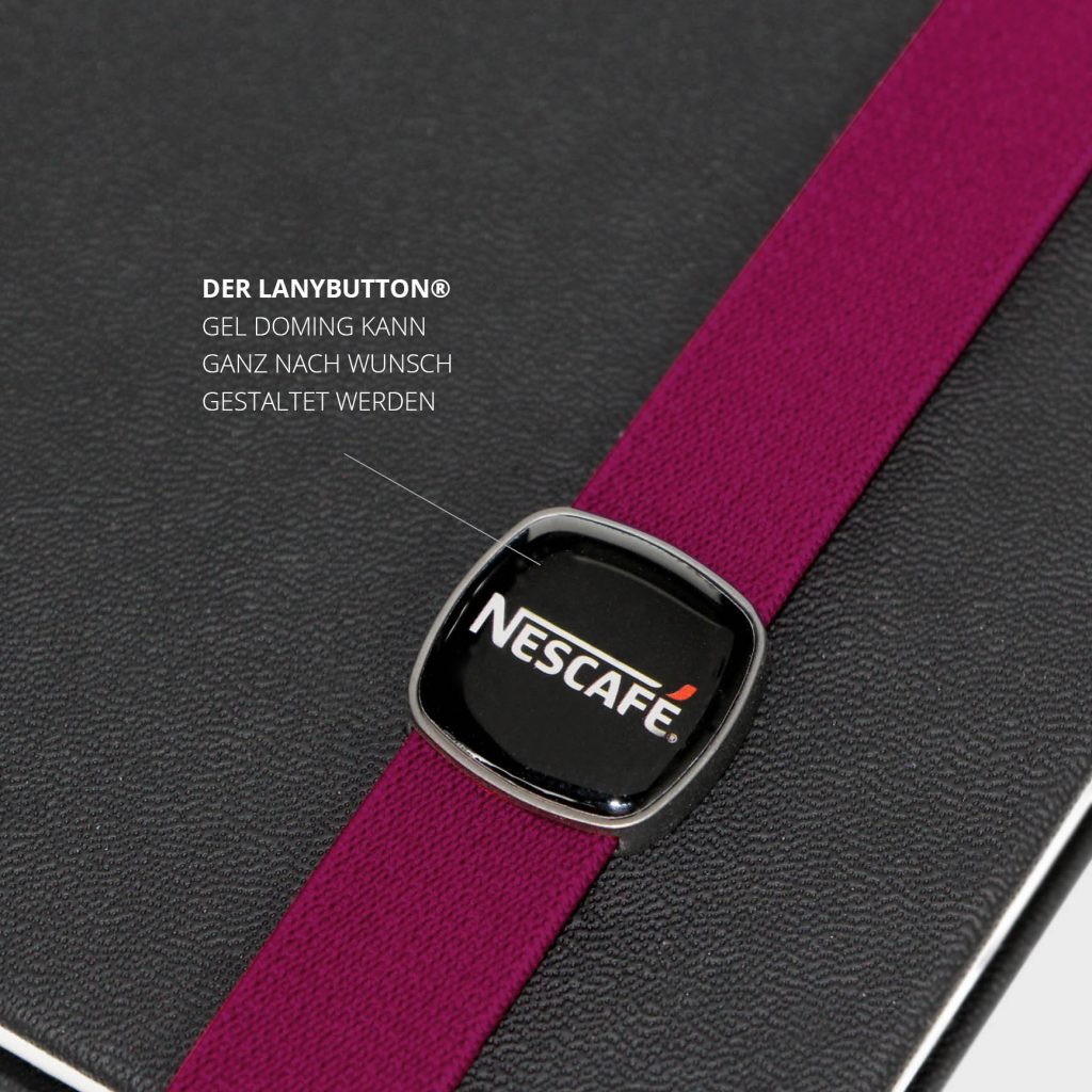 Detailaufnahme des quadratischen LanyButtons mit Nescafé Logo im Gel Doming auf himbeerfarbenem Lanyband