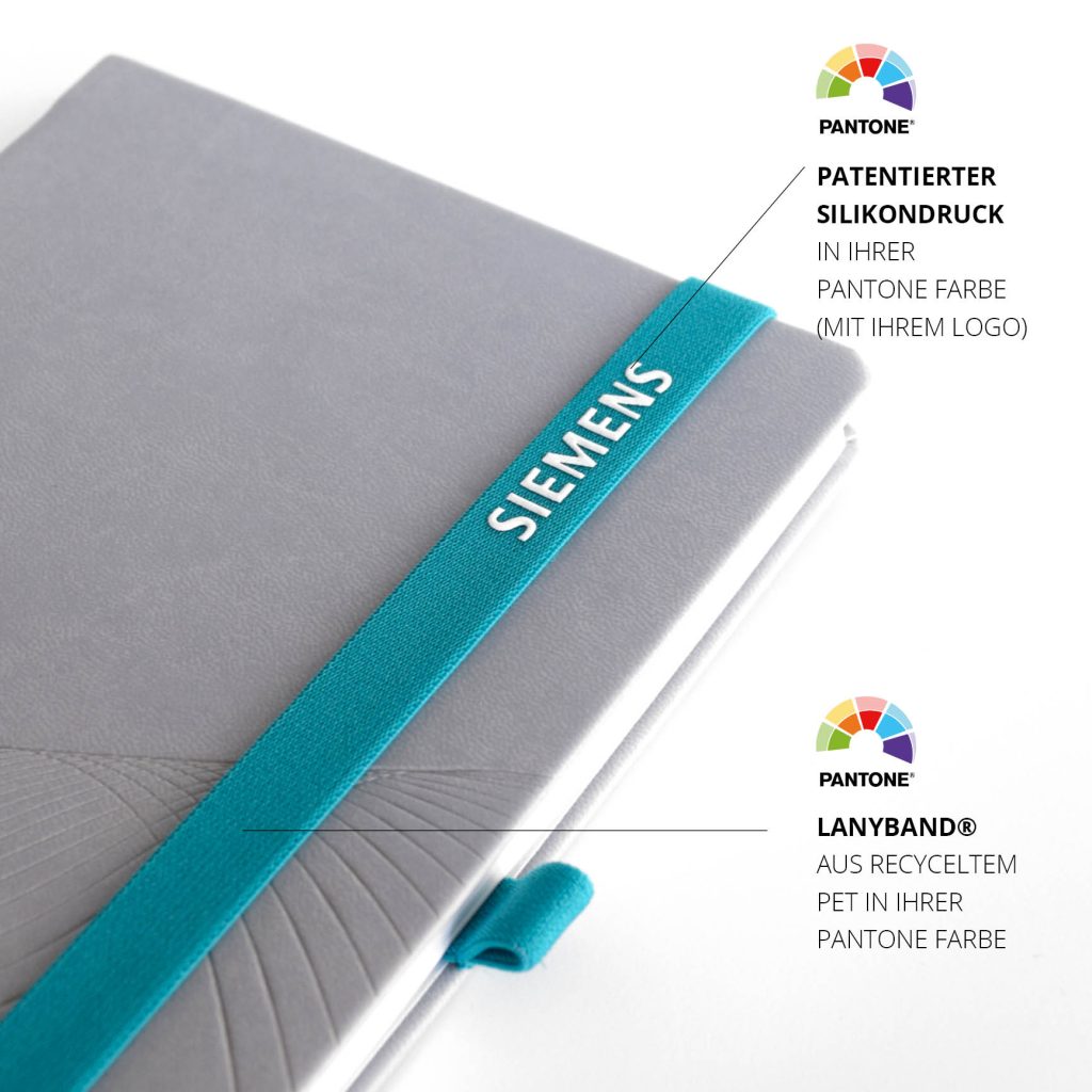 Detailansicht des türkisfarbenen Lanybands mit weißem SIEMENS Silikondruck in Pantone Farbe auf hellgrauem Notizbuch
