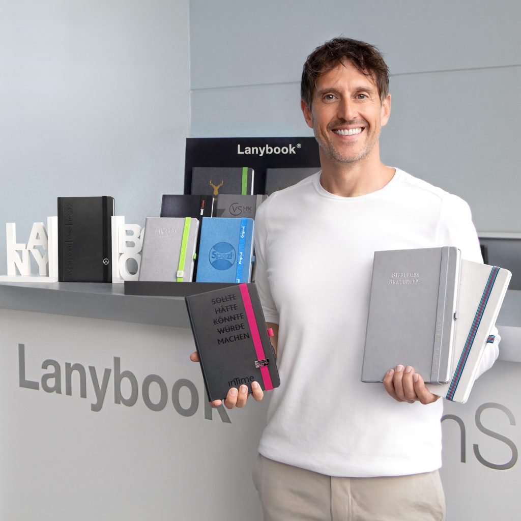 Mitarbeiter von Lanybook® präsentiert individuelle Notizbücher mit Logo im Showroom