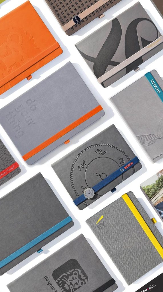 Individuelle Notizbücher im Corporate Design mit Logo und farbigen Lanybändern als hochwertige Werbegeschenke für Unternehmen